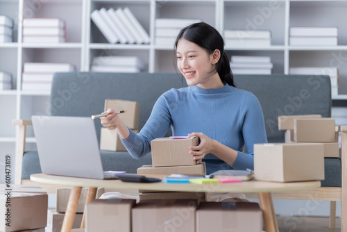 Startup SME small business entrepreneur of freelance Asian woman using a laptop with box Cheerful success Asian woman her hand lifts up online marketing packaging box and delivery SME 