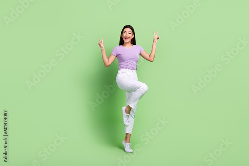 Full length size photo of funky young japanese woman have fun show v-sign greetings wear purple t-shirt isolated on green color background