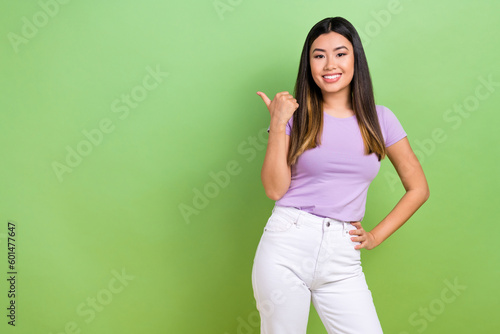 Photo of young chinese girl point finger empty space useful tips how improve your language skills isolated on green color background