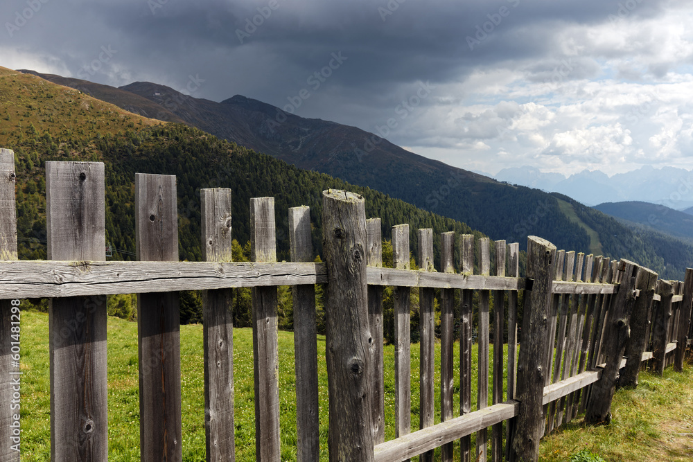 A wooden fence in front of the Carnic Alps with a dramatic sky, Alps, South Tyrol, Italy, Europe