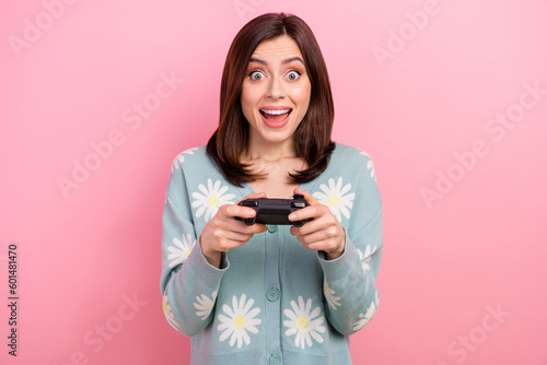 Closeup portrait of young funny surprised woman wear shirt play console xbox one playstation hold gamepad isolated on pink color background