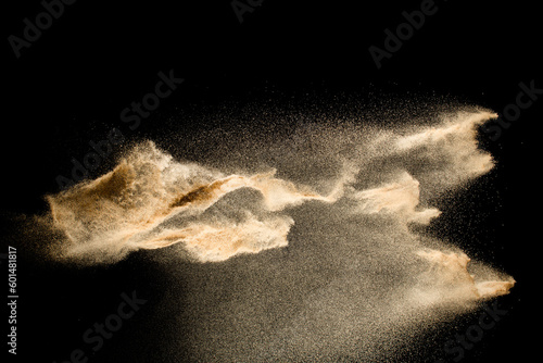 Abstract sand cloud.Golden colored sand splash agianst dark background.Yellow sand fly wave in the air. Sand explode on black background ,throwing freeze stop motion concept.