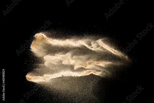 Abstract sand cloud.Golden colored sand splash agianst dark background.Yellow sand fly wave in the air. Sand explode on black background ,throwing freeze stop motion concept. photo