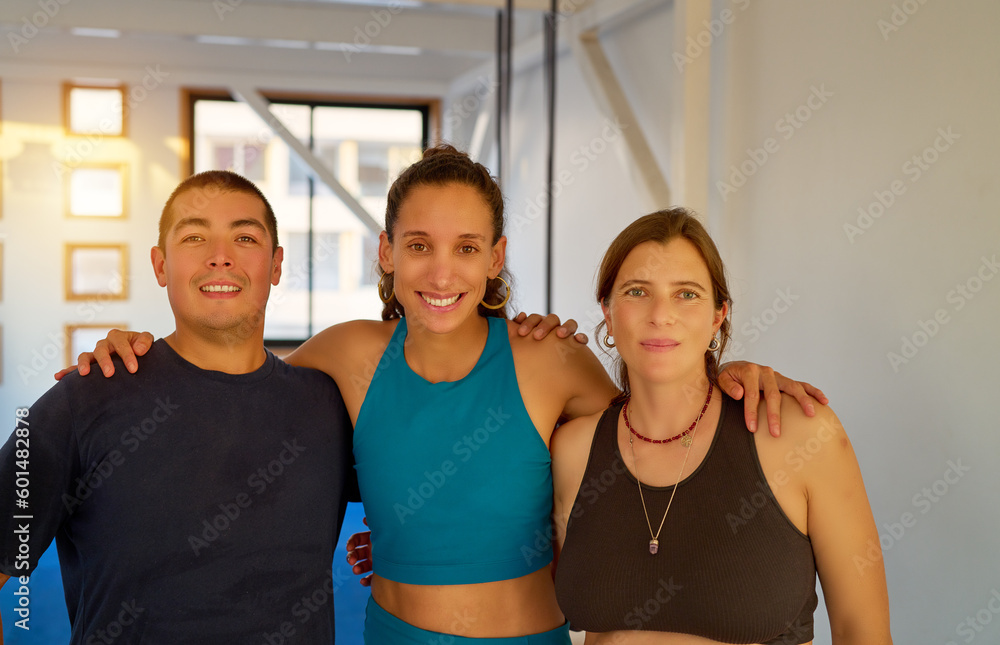 portrait standing mixed group of latinos embracing in a fitness or yoga studio	
