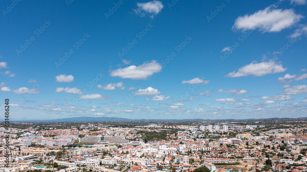 Aerial photo of the beautiful town in Albufeira in Portugal showing the pretty town on a hot summers day with blue skies and white fluffy clouds in the sky in the summer time.
