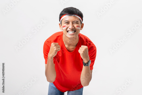 Young Indonesian man very happy and excited with arms raised celebrate Indonesia independence day 17 August isolated on white background. Dirgahayu 78 Tahun Kemerdekaan Indonesia.