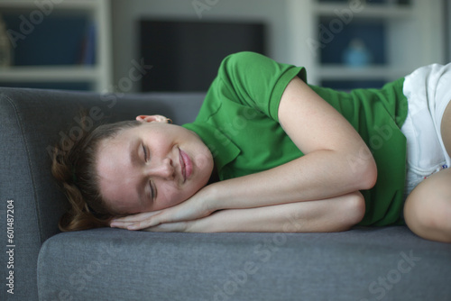 happy young woman sit on sofa and have a rest, relaxing living room at home in green polo t-shirt