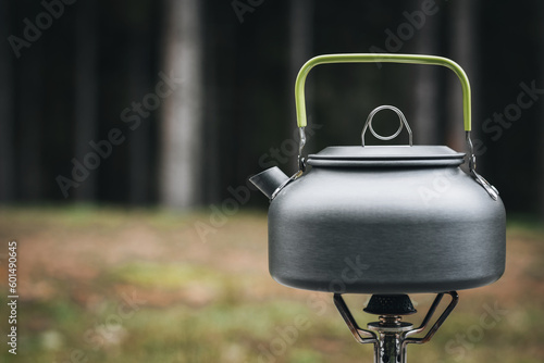 Cooking, heating a tourist kettle on a portable gas burner with a red gas cylinder. Cooking in a tourist campsite in the mountains. Summer outdoor activities