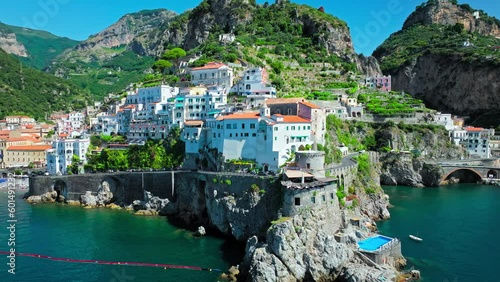 Aerial drone view of a Road in a dramatic natural setting below steep cliffs. Cars driving on a scenic Mediterranean Coastal Road with Amalfi Coast in the background in ProRes 4K.