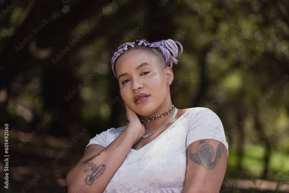 A nonbinary model of multiracial African American and Latinx ancestry poses in a leafy forest. Their purple braids shine brightly, alluding to themes of queer identity and gender expression. A nonbinary model of multiracial African American and Latinx ancestry poses in a leafy forest. Their purple braids shine brightly, alluding to themes of queer identity and gender expression.