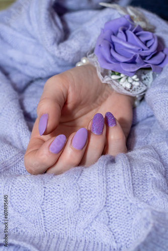 Close-up of well-groomed female nails with lilac and purple color gel. Beautiful clear fingers of a young girl with nice manicure. Brilliant colors and soft tones. Close-up of hand with a rose.