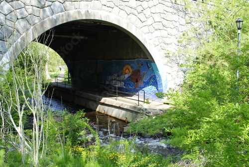 Stone arch bridge with lovely mural over the river in Brewster Gardens, a historical site and public park in Plymouth, MA. photo