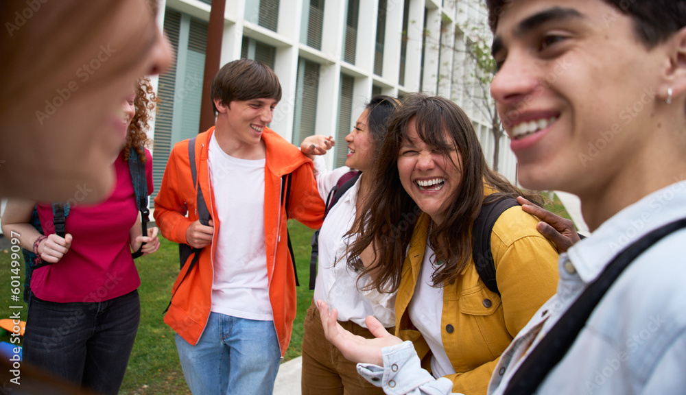 Group of multiracial young students having fun walking together on college campus. Happy teens hanging out outside of school. Generation z people laughing outdoors. Scholarship concept