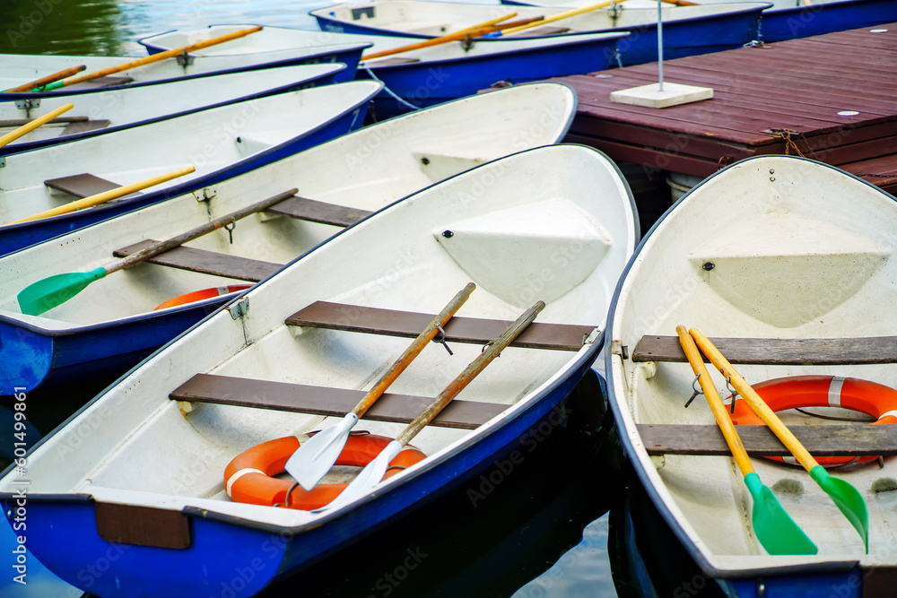 Pleasure boats with oars and lifebuoys near the wooden pier on the lake Pleasure boats with oars and lifebuoys near the wooden pier on the lake