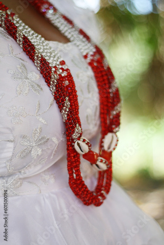 Tipico colar de missangas símbolo do orixá na religião afro, usado na umbanda como representação sobre vestido branco de renda em ritual de fé photo