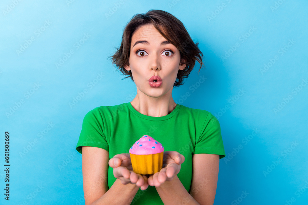 Photo of excited impressed woman wear green t-shirt holding arms little muffin isolated blue color background Photo of excited impressed woman wear green t-shirt holding arms little muffin isolated blue color background