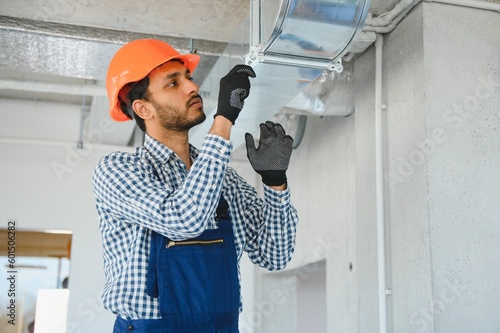 hvac services - indian worker install ducted pipe system for ventilation and air conditioning in house