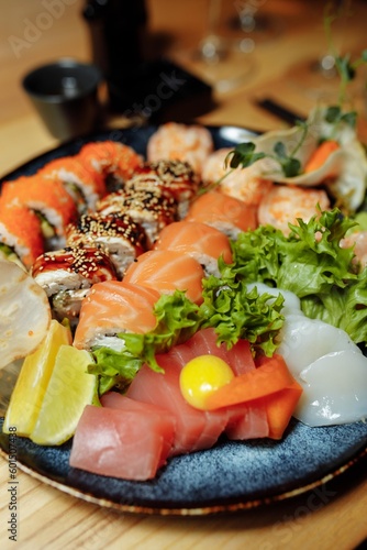 Mixed Sushi Set nigiri, rolls and sashimi served in traditional Japan black Sushioke round plate.