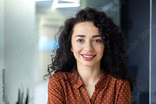 Fotografie, Tablou Close up photo portrait of beautiful Latin American woman with curly hair , businesswoman inside office building smiling and looking at camera