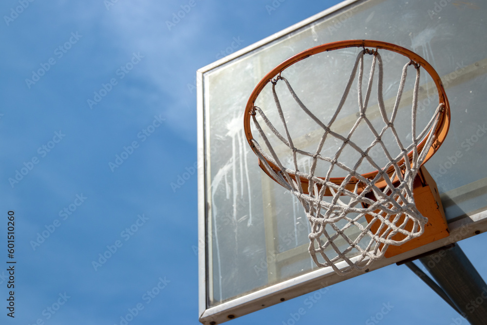 Outdoor neighborhood basketball court park and recreational area, Basketball net and backboard against sunny blue sky with copy space