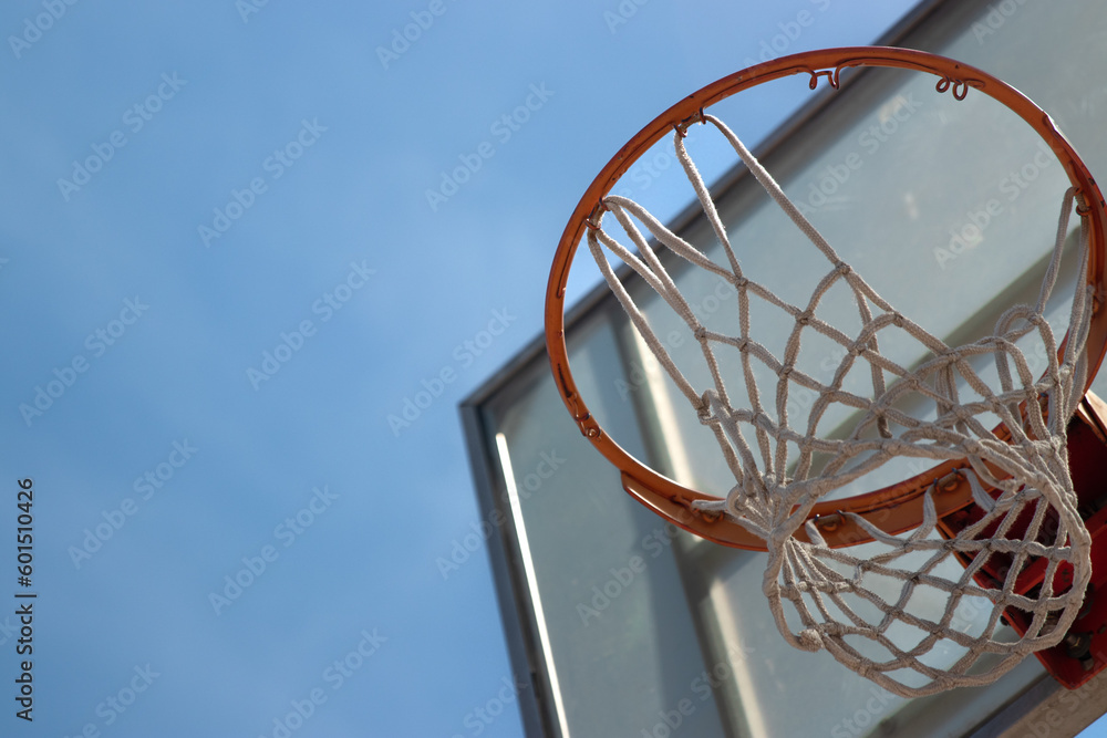 Outdoor neighborhood basketball court park and recreational area, Basketball net and backboard against sunny blue sky with copy space