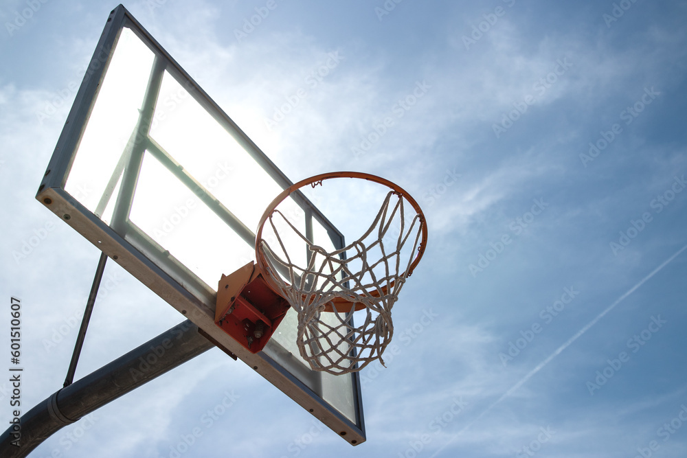 Outdoor neighborhood basketball court park and recreational area, Basketball net and backboard against sunny blue sky with copy space