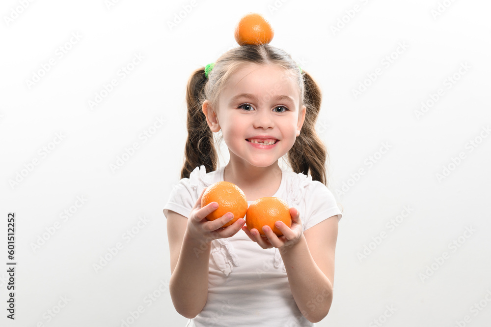 Portrait of a small beautiful girl on a white background with tangerines in her hands. Portrait of a small beautiful girl on a white background with tangerines in her hands.