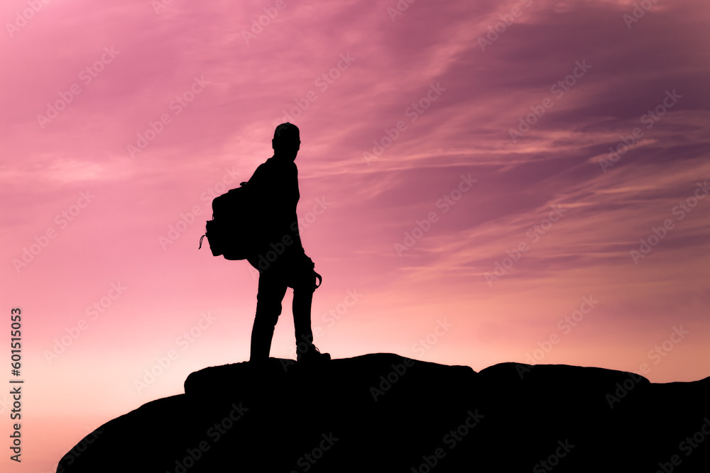 Silhouette of hiker adventurer against a purple sunset sky