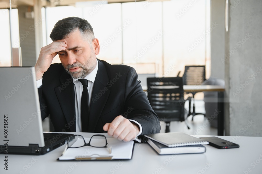 Tired stressed office worker sitting at desk and thinking, he is rubbing his eyes and feeling exhausted. Tired stressed office worker sitting at desk and thinking, he is rubbing his eyes and feeling exhausted.