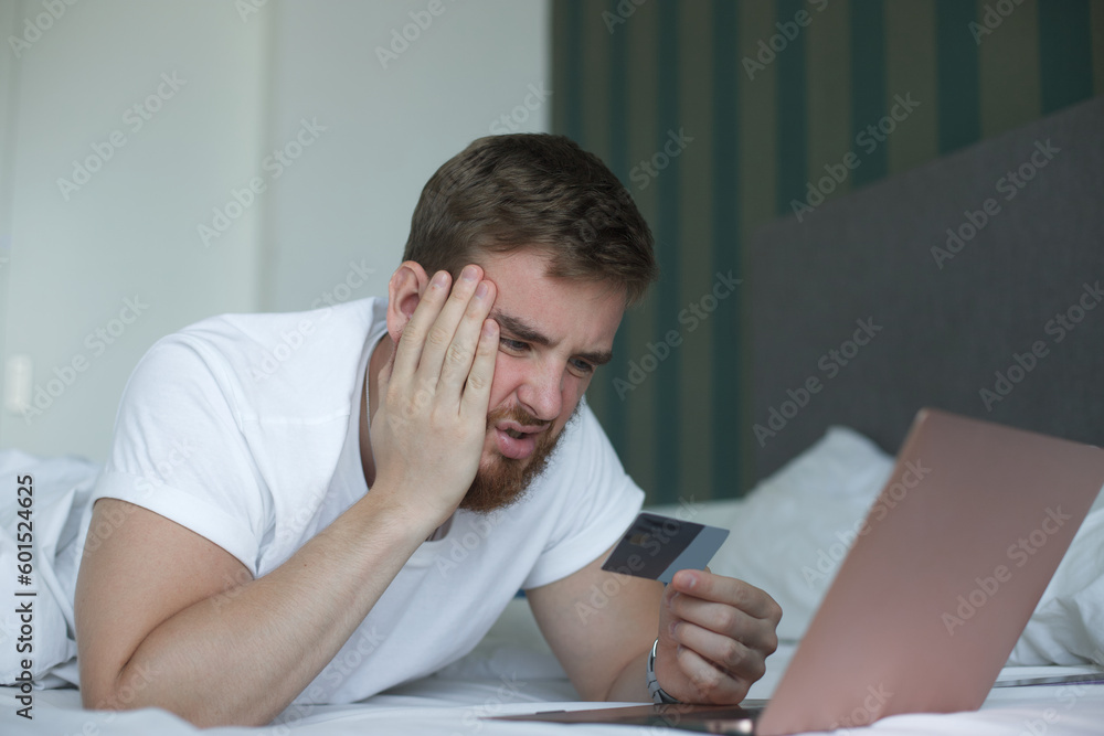 Nervous sad upset confused young man, stressed worried guy having problem with paying, buying online, payments with credit blocked bank card, looking at screen, monitor of laptop. Internet fraud Nervous sad upset confused young man, stressed worried guy having problem with paying, buying online, payments with credit blocked bank card, looking at screen, monitor of laptop. Internet fraud
