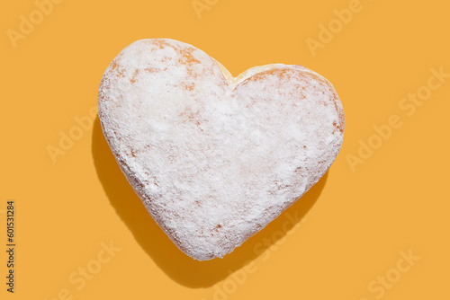 Heart shaped donut with glaze on yellow pastel background photo