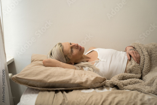Sleepy young albino woman stretching herself in soft bed