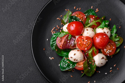 Delicious fresh salad with mozzarella cheese, cherry tomatoes, herbs, salt and spices