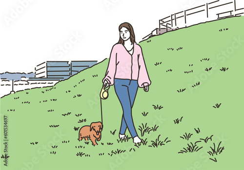 屋外で犬と散歩する若い女性
