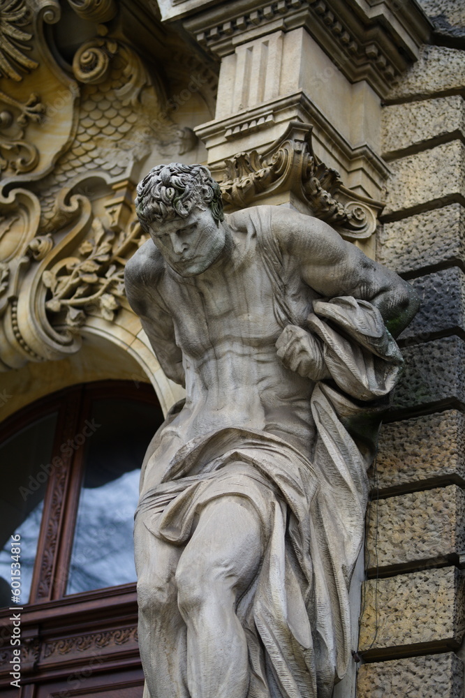 Klasyczny posąg umięśnionego mężczyzny dźwigającego coś na plecach, element architektury budynku w mieście