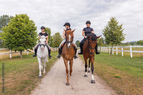 Three female riders riding horses along the trail. Recreation and leisure activity concepts. © 24K-Production