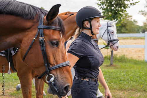 Young female jockey in helmet petting her horse in countryside © 24K-Production