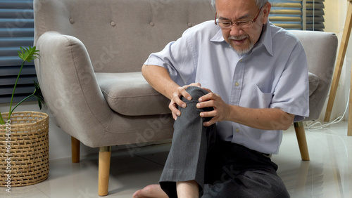 Fotografie Elderly asian man touching knee hurt painfully problem sitting on floor at home
