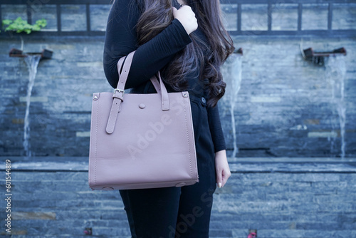 woman in a black outfit holding and carrying a leather bag with hair.