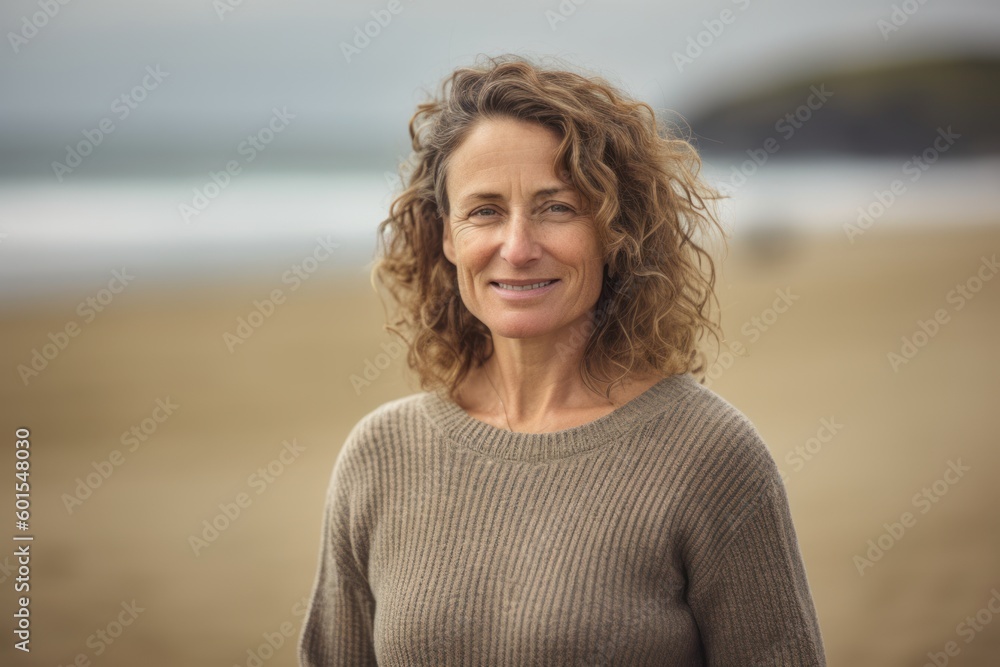 Portrait of mature woman smiling at camera on the beach in autumn Portrait of mature woman smiling at camera on the beach in autumn