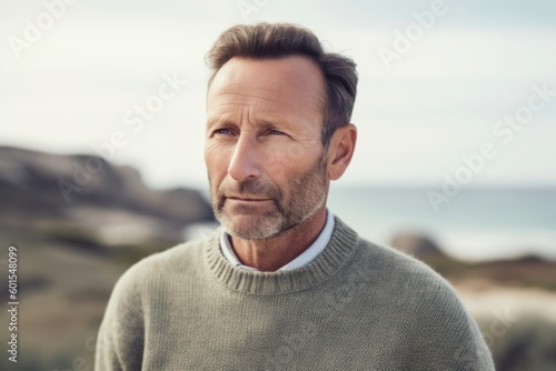 Medium shot portrait photography of a tender man in his 40s wearing a cozy sweater against a summer landscape or beach background. Generative AI