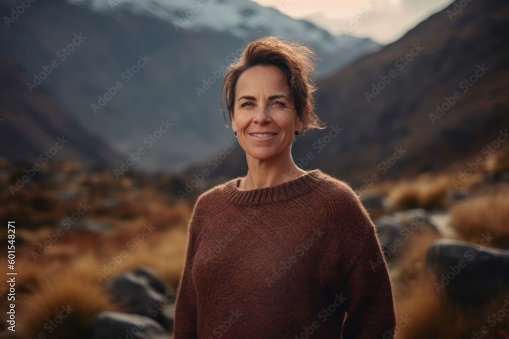 Portrait of a smiling middle-aged woman in a sweater standing in the mountains. Portrait of a smiling middle-aged woman in a sweater standing in the mountains.