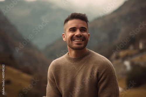 Portrait of a handsome young man smiling and looking at camera in the mountains