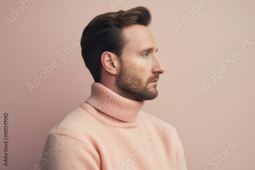 side view of handsome man in pink sweater looking away isolated on grey