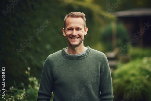 Portrait of a young handsome man in a green sweater standing in the garden.