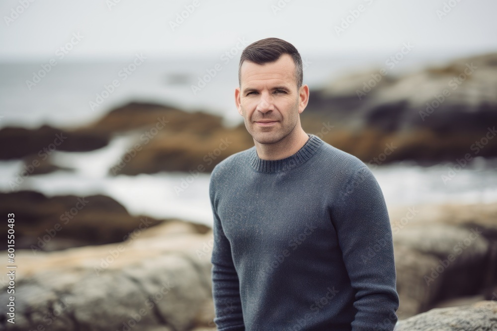 Portrait of a handsome man standing on a rock by the sea Portrait of a handsome man standing on a rock by the sea