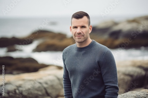 Portrait of a handsome man standing on a rock by the sea