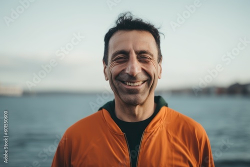 Portrait of a smiling young man in sportswear standing by the sea.