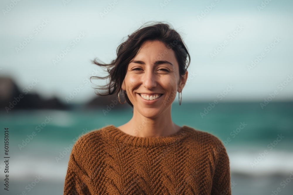 Portrait of a smiling young woman standing by the sea in sweater Portrait of a smiling young woman standing by the sea in sweater