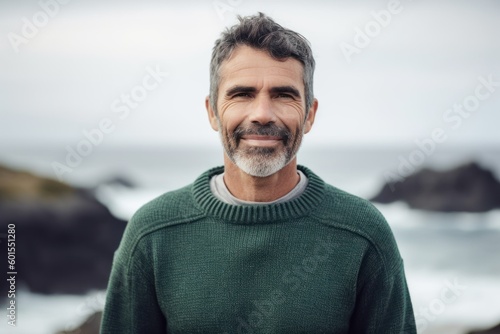 Portrait of handsome mature man standing on the beach at the coast